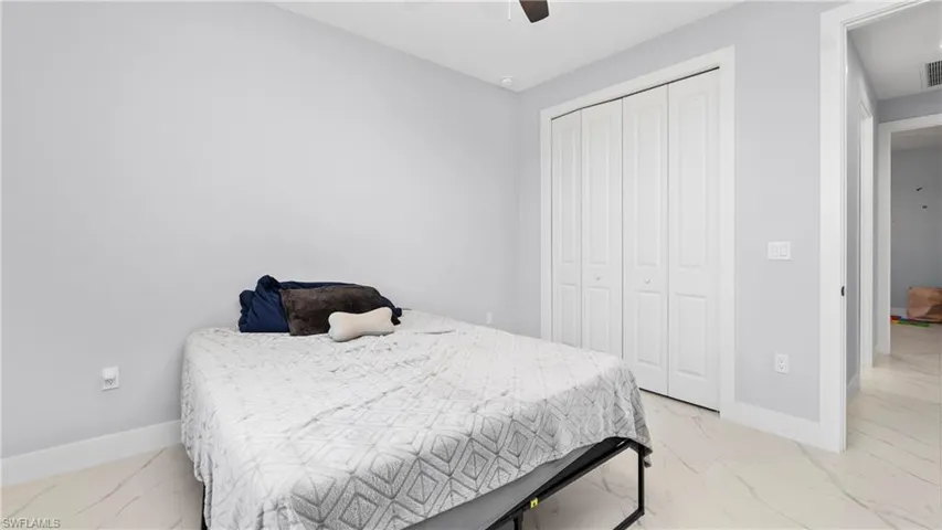 Bedroom with a closet, light marble finish floors, and a ceiling fan