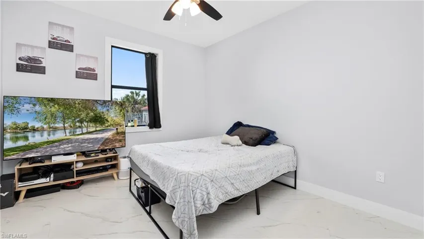 Bedroom featuring a ceiling fan and light marble finish floors
