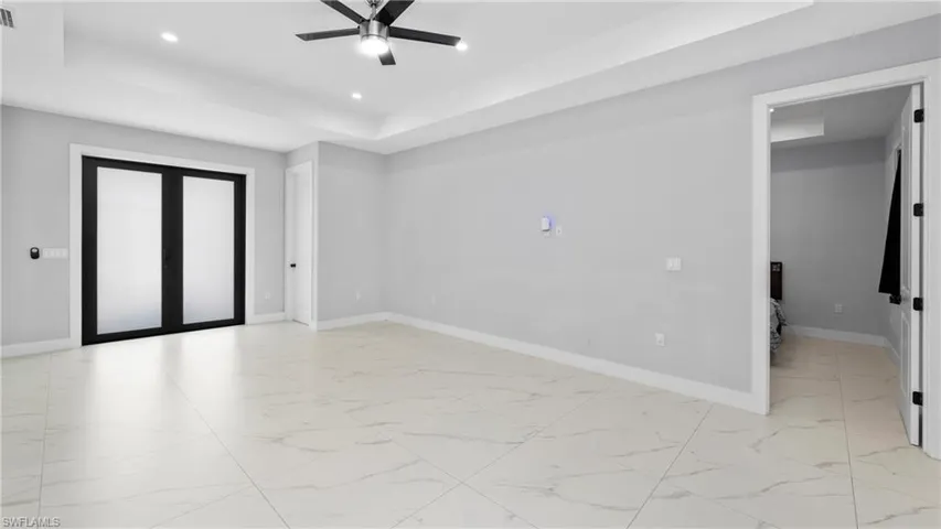 Unfurnished room with a tray ceiling, light marble finish floors, a ceiling fan, and recessed lighting