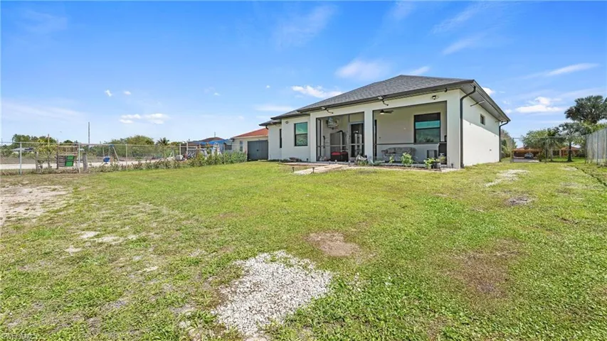 Rear view of house featuring a fenced backyard, a ceiling fan, stucco siding, and a patio area
