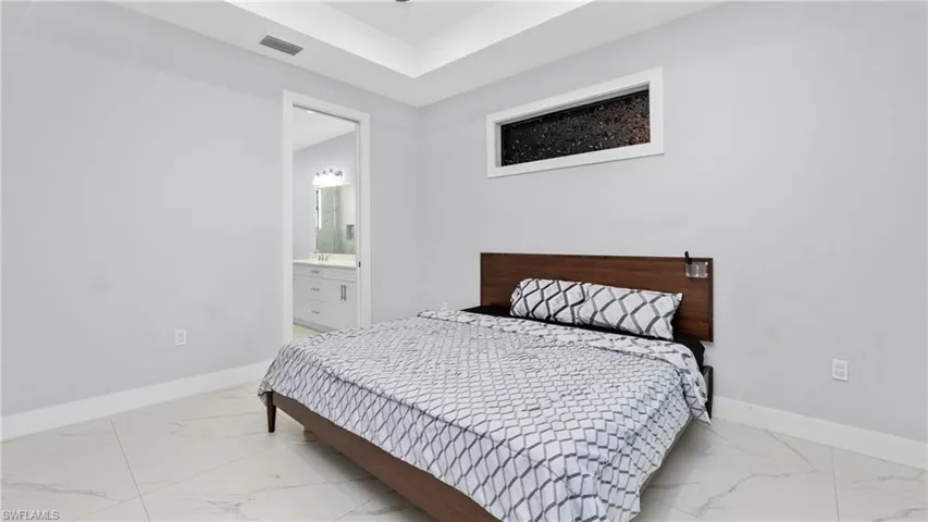 Bedroom with ensuite bathroom and light marble finish floors