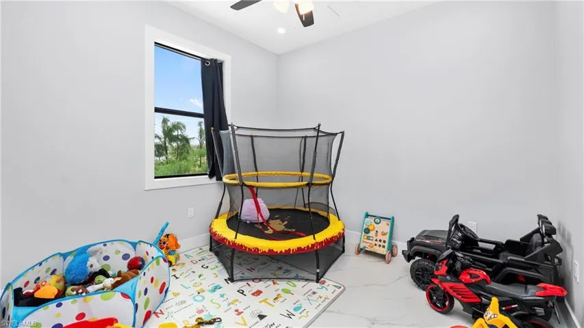 Playroom featuring light marble finish flooring and a ceiling fan