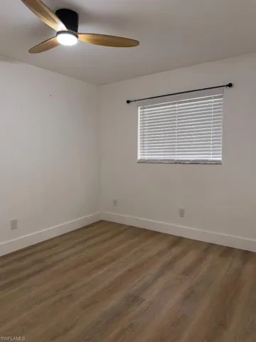 Room featuring wood-finish flooring, white walls, and white baseboards