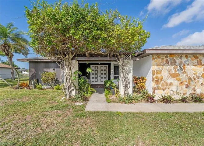 Entrance to property with stone siding and a lawn