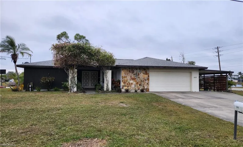 Ranch-style home featuring a carport, a garage, and a front yard