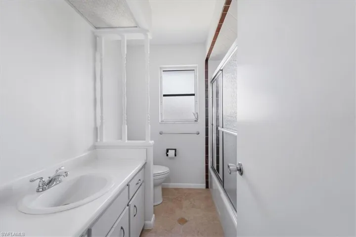 Bathroom with vanity, tile patterned flooring, toilet, combined bath / shower with glass door, and baseboards