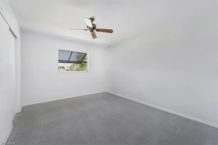 Carpeted bedroom with baseboards and a ceiling fan