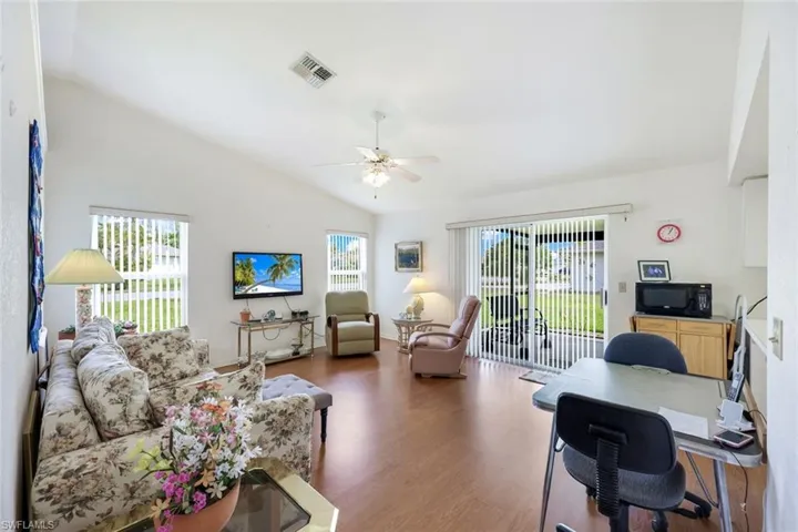 Home office featuring lofted ceiling, a wealth of natural light, wood finished floors, and a ceiling fan