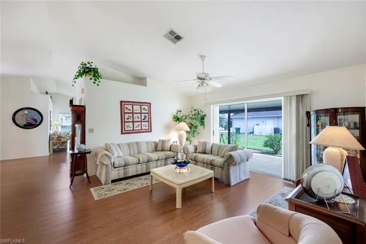 Living room featuring lofted ceiling, ceiling fan, wood finished floors, and visible vents