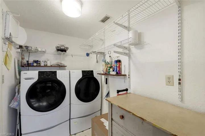 Clothes washing area featuring independent washer and dryer, a textured ceiling, laundry area, and visible vents
