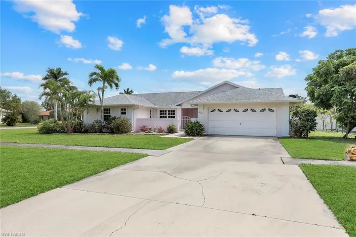 Ranch-style home featuring stucco siding, an attached garage, driveway, a front yard, and a shingled roof