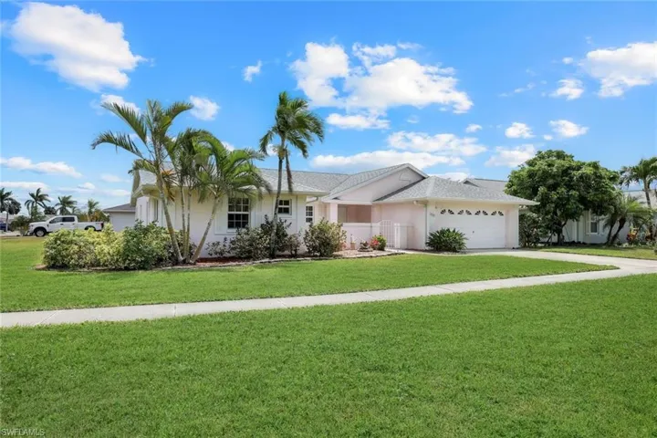 Ranch-style home featuring stucco siding, driveway, a garage, and a front lawn