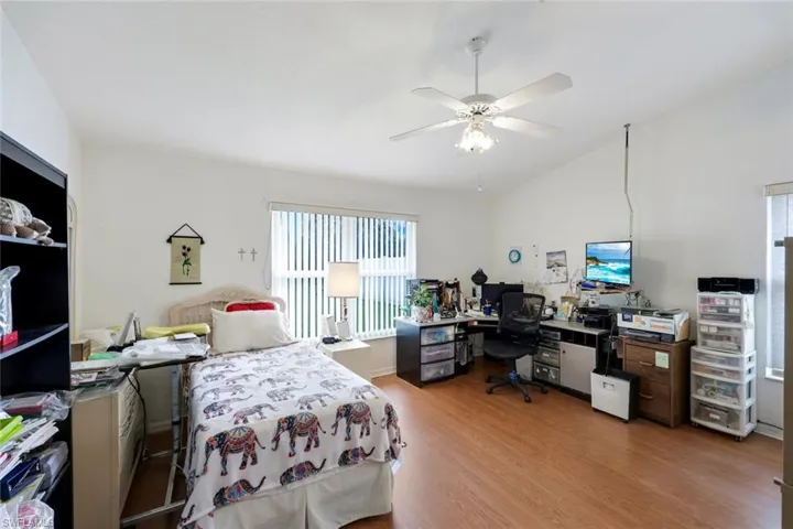 Bedroom with a ceiling fan, vaulted ceiling, and light wood finished floors