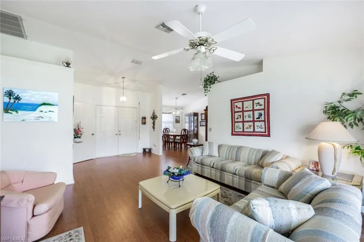Living room featuring a ceiling fan, wood finished floors, lofted ceiling, and visible vents