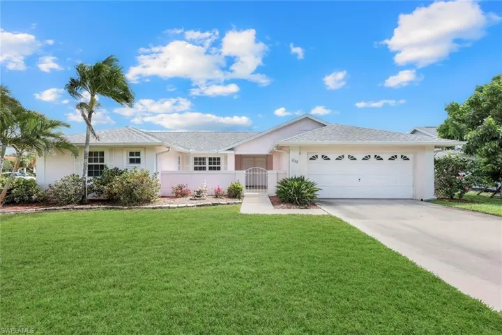 Ranch-style house featuring stucco siding, driveway, a front yard, a gate, and a garage