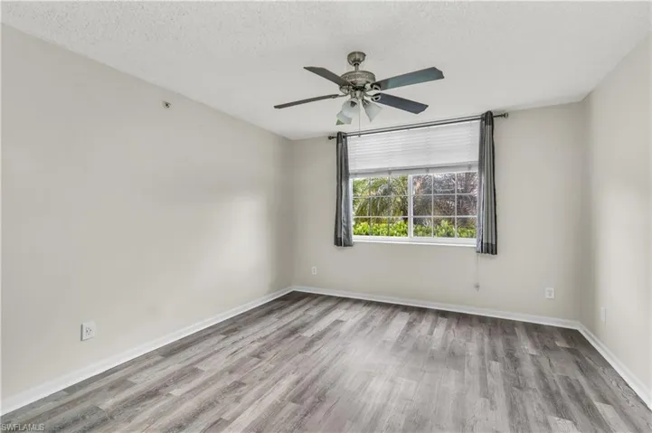 Unfurnished room with ceiling fan, a textured ceiling, and light wood-type flooring