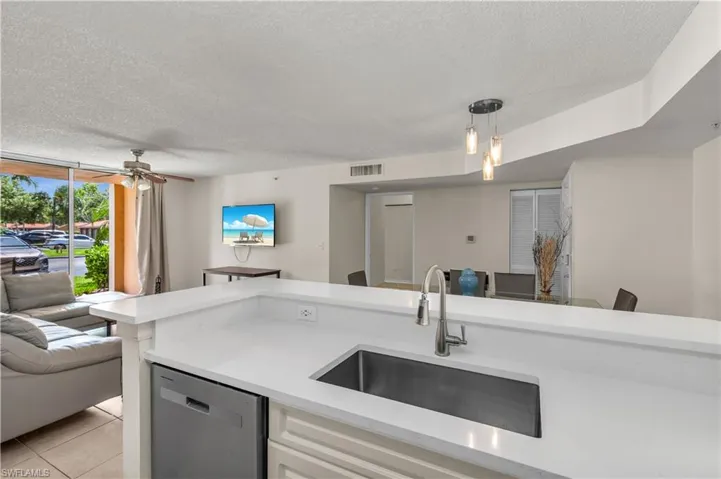 Kitchen featuring open floor plan, dishwasher, a textured ceiling, a ceiling fan, and light stone countertops