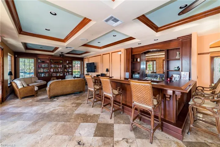 Bar area featuring ceiling fan, crown molding, plenty of natural light, coffered ceiling, and open shelves