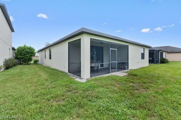 Back of house featuring a lawn, a sunroom, a ceiling fan, and stucco siding