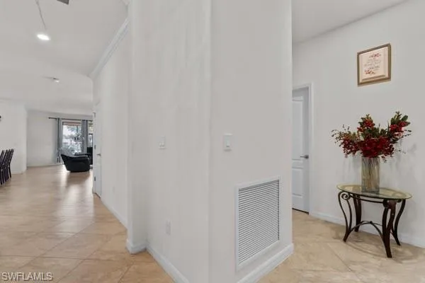 Hallway with light tile patterned flooring, crown molding, and recessed lighting