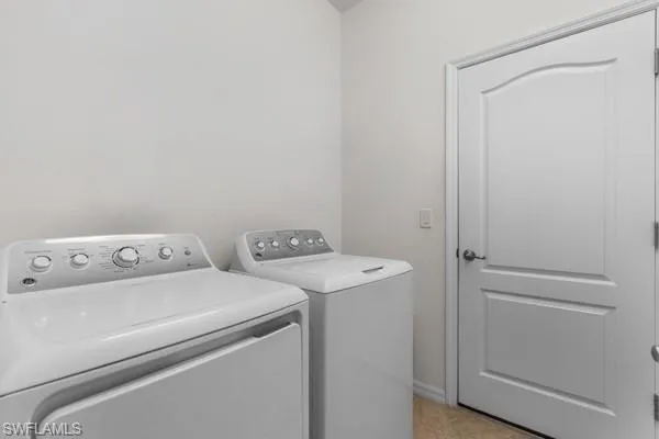 Laundry area with washing machine and clothes dryer and light tile patterned floors