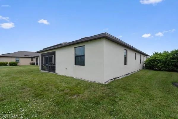 View of home's exterior with stucco siding, a lawn, and a sunroom