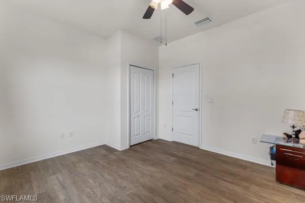 Unfurnished bedroom featuring dark wood-style flooring, ceiling fan, and a closet