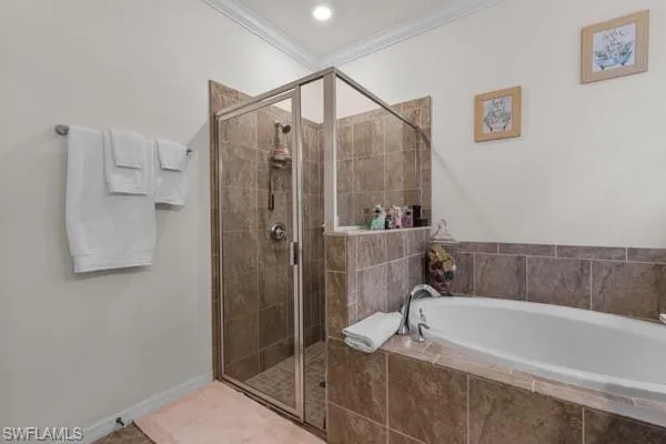 Bathroom with a stall shower, a garden tub, crown molding, and tile patterned flooring