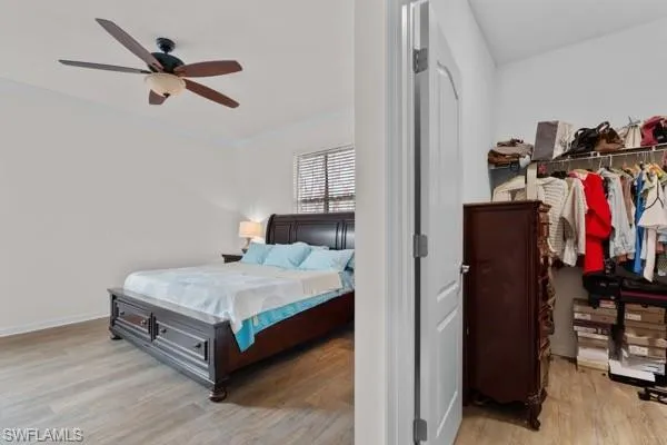 Bedroom with light wood-type flooring, crown molding, and a ceiling fan