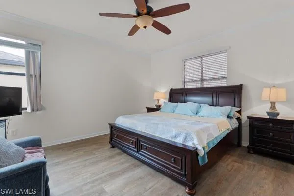 Bedroom with ornamental molding, light wood-type flooring, and a ceiling fan