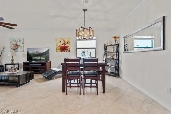 Dining space with crown molding, a chandelier, light tile patterned flooring, and a ceiling fan