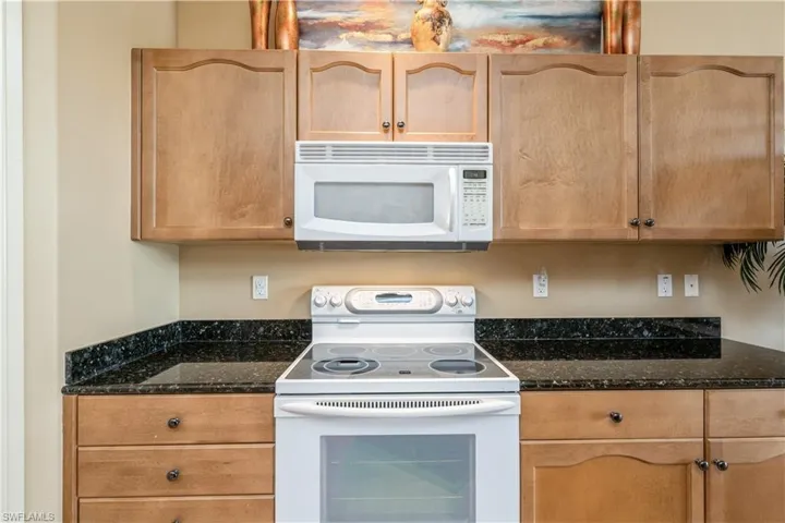 Kitchen with white appliances and dark stone countertops