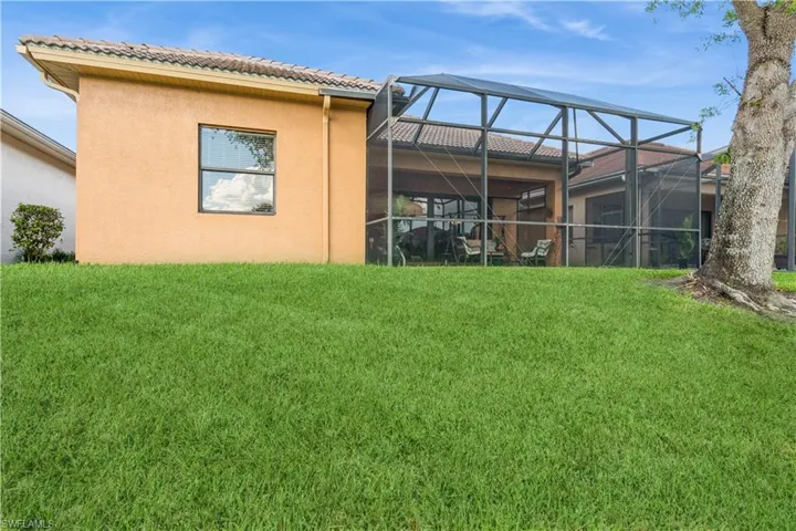 Rear view of property with a yard and glass enclosure