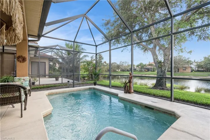 View of swimming pool with a lanai, a water view, and a patio