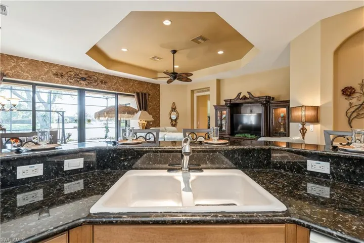 Kitchen with a raised ceiling, sink, and dark stone counters