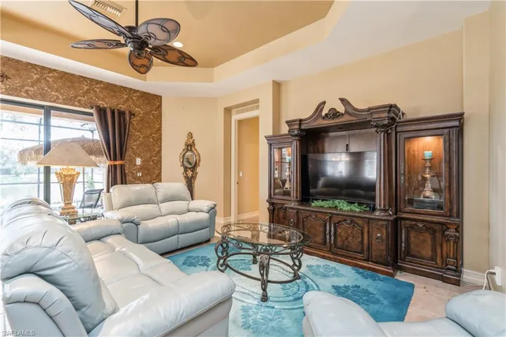 Tiled living room with a tray ceiling and ceiling fan