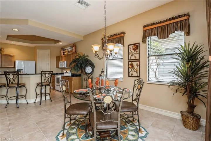 Dining room with a raised ceiling, light tile patterned floors, and a notable chandelier