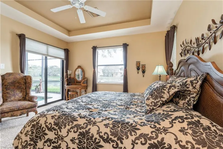 Bedroom featuring access to exterior, carpet, a raised ceiling, and ceiling fan