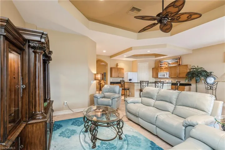 Tiled living room with a tray ceiling and ceiling fan