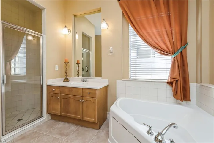 Bathroom with tile patterned flooring, plenty of natural light, shower with separate bathtub, and vanity