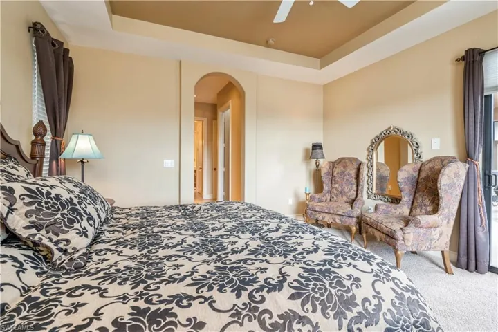 Carpeted bedroom with a raised ceiling and ceiling fan