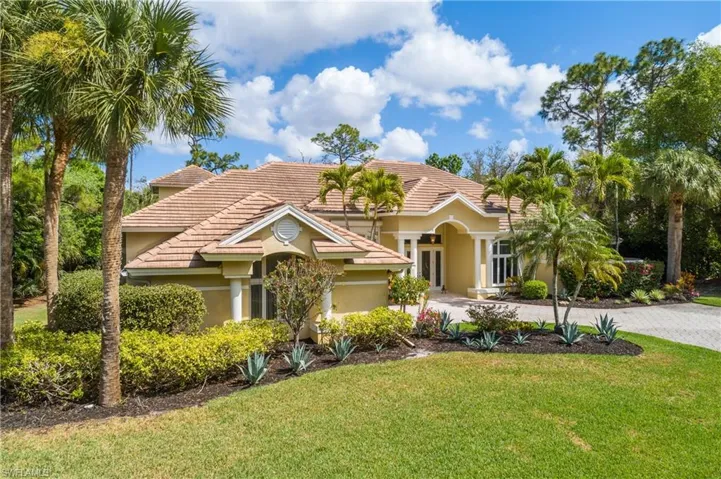 View of front of property with a front lawn, driveway, stucco siding, and a tiled roof