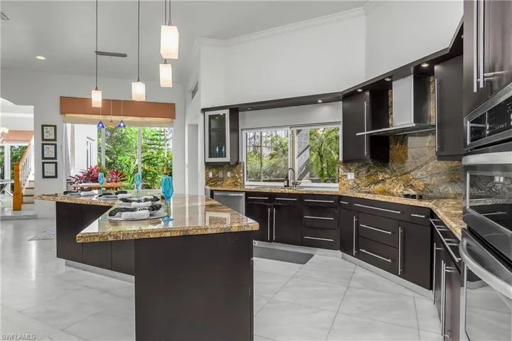 Kitchen featuring stainless steel appliances, tasteful backsplash, a center island, ornamental molding, and healthy amount of natural light