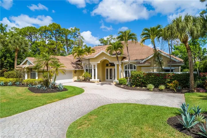 View of front of property featuring french doors, stucco siding, and a front lawn