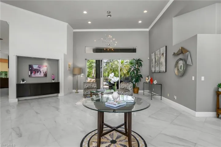 Living room with a high ceiling, a chandelier, and crown molding