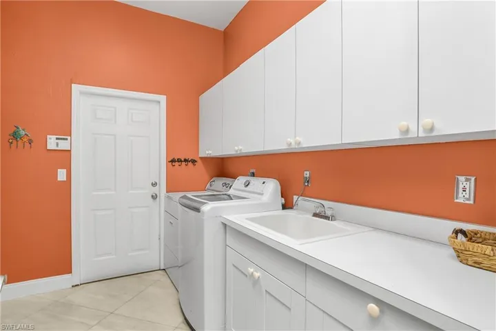 Laundry area featuring cabinet space, washer and dryer, and light tile patterned floors