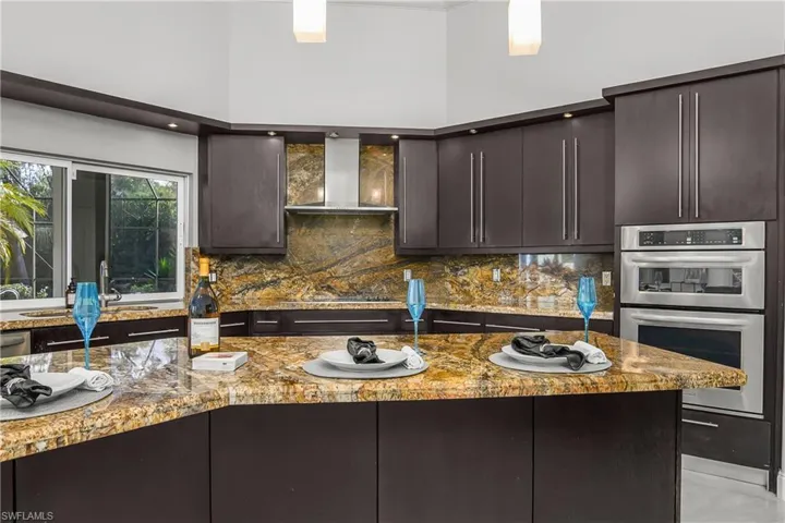 Kitchen featuring stainless steel oven, light stone counters, tasteful backsplash, and modern cabinets