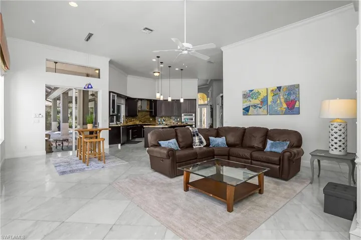 Living area with ornamental molding, ceiling fan, and a high ceiling leading to Kitchen and Lanai