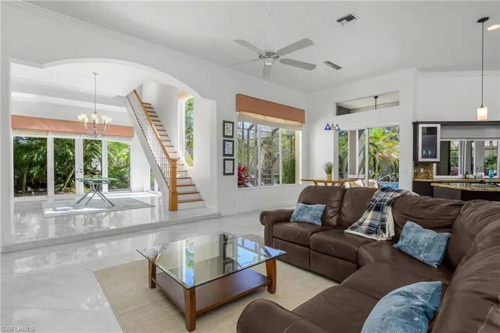 Living area with ornamental molding, ceiling fan, suspended lighting, and plenty of natural light