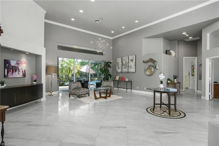Formal Living room featuring a high ceiling, crown molding, hanging lights, and light marble finish floors